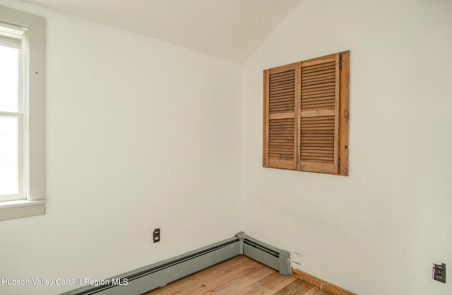 empty room with baseboard heating, vaulted ceiling, and hardwood / wood-style floors