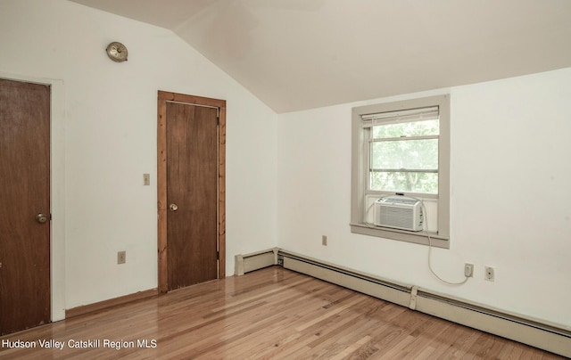 empty room featuring vaulted ceiling, light hardwood / wood-style flooring, cooling unit, and baseboard heating