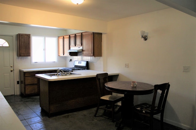 kitchen with decorative backsplash, stove, kitchen peninsula, and sink