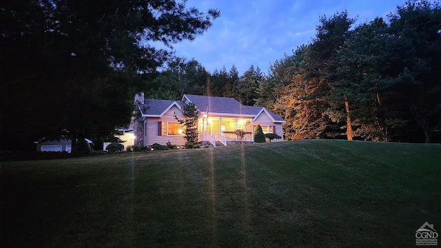view of front facade with a front yard, a chimney, and a forest view
