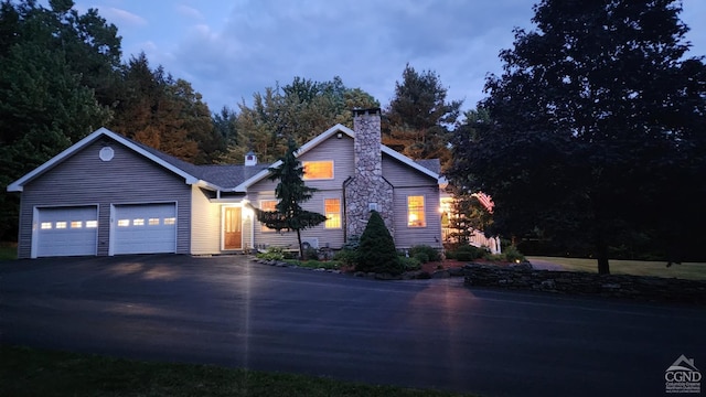 view of front of home featuring a chimney, asphalt driveway, and an attached garage