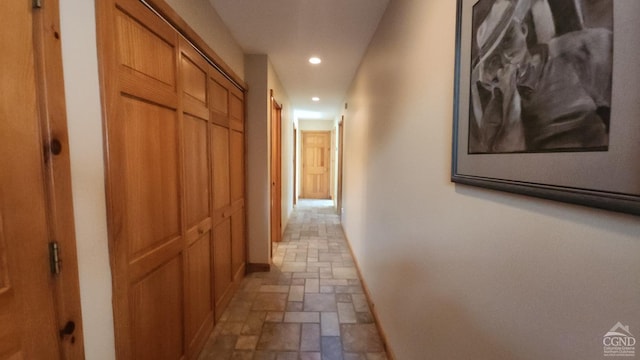 corridor with stone finish flooring, recessed lighting, and baseboards