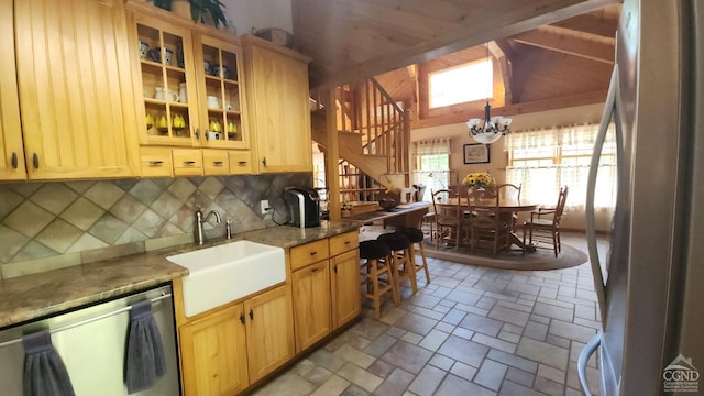 kitchen featuring stainless steel appliances, a sink, backsplash, a chandelier, and light stone finish floors