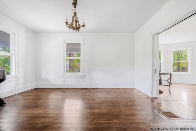 unfurnished dining area featuring a wealth of natural light, a notable chandelier, and hardwood / wood-style flooring