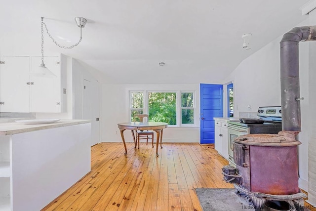 kitchen with electric stove, hanging light fixtures, vaulted ceiling, light wood-type flooring, and white cabinetry