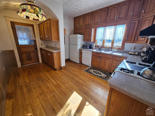 2322 US Route 9, Hudson, NY 12534 - kitchen featuring white appliances, light wood finished floors, a sink, brown cabinets, and wall chimney range hood