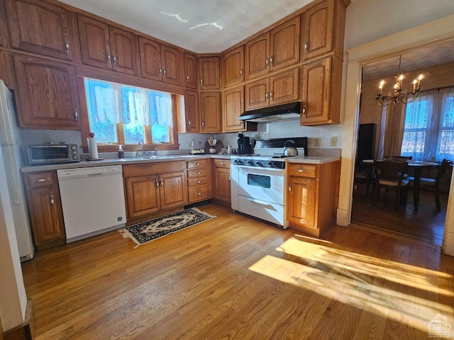 2322 US Route 9, Hudson, NY 12534 - kitchen featuring white appliances, under cabinet range hood, a chandelier, light wood-style floors, and tasteful backsplash
