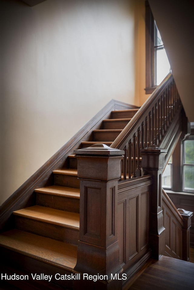 stairway featuring a healthy amount of sunlight and hardwood / wood-style flooring