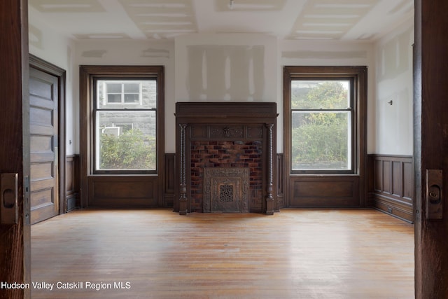 unfurnished living room featuring light hardwood / wood-style floors and a brick fireplace