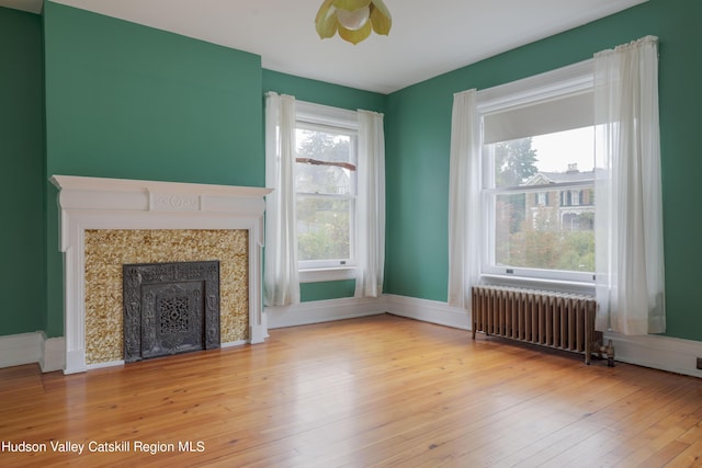 unfurnished living room featuring radiator heating unit and light wood-type flooring