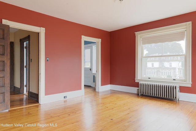 unfurnished room featuring radiator and hardwood / wood-style flooring