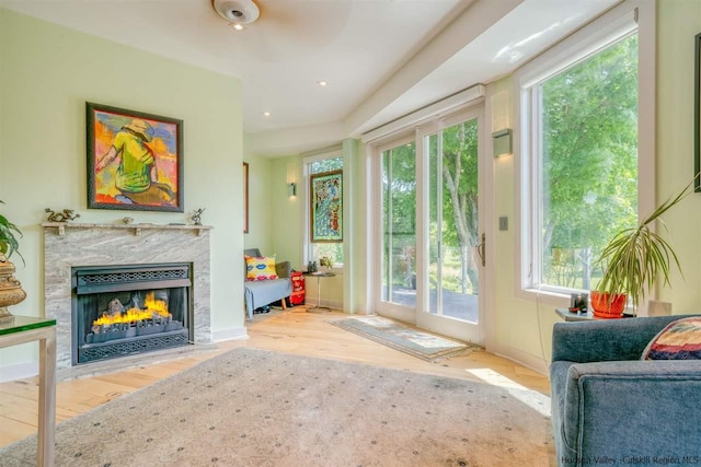 doorway featuring recessed lighting, a high end fireplace, wood finished floors, and a healthy amount of sunlight