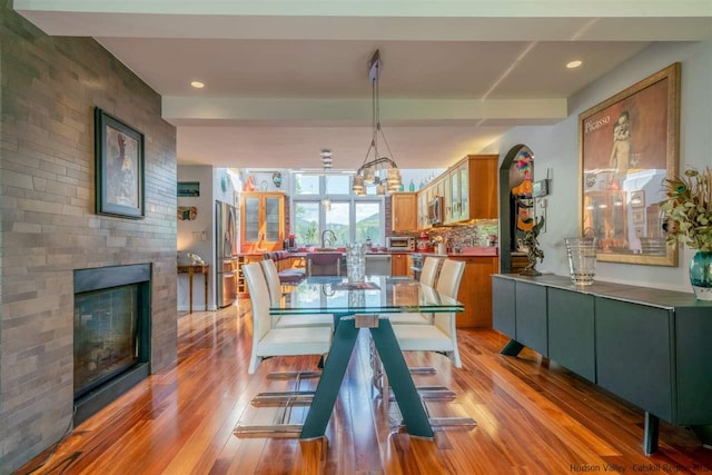 dining area featuring light wood-style floors, recessed lighting, a glass covered fireplace, and a chandelier