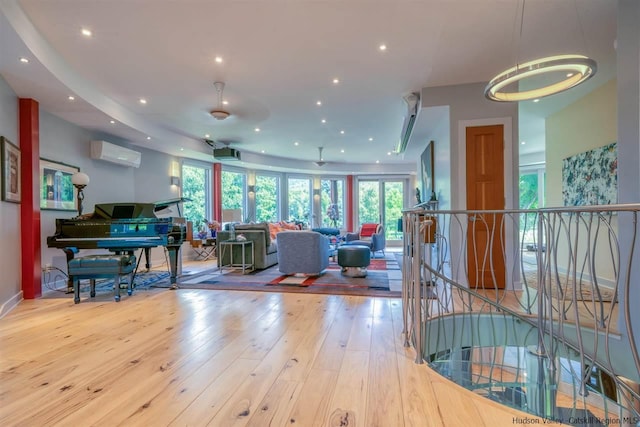 living area featuring recessed lighting, a wall unit AC, a healthy amount of sunlight, and hardwood / wood-style floors