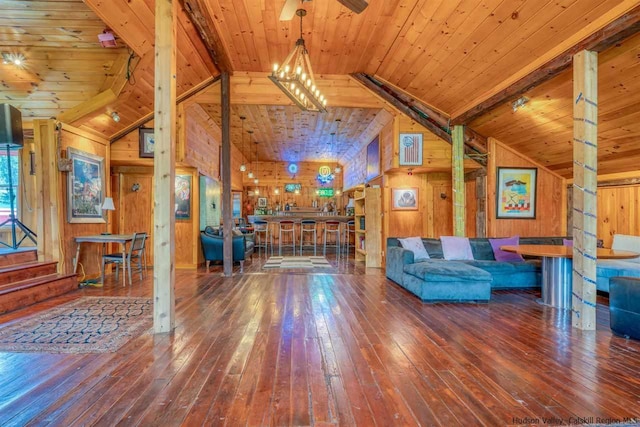 living area featuring wooden walls, vaulted ceiling with beams, and wood-type flooring
