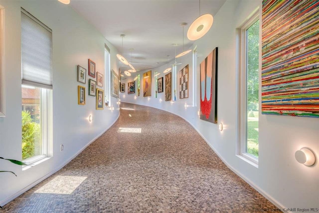 corridor featuring baseboards and plenty of natural light
