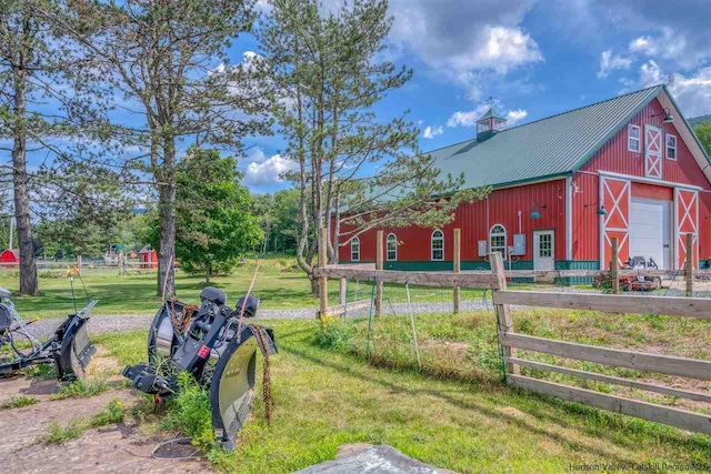 view of yard featuring a barn, fence, an outdoor structure, and a garage