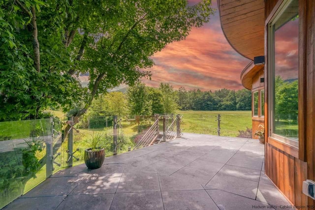 patio terrace at dusk featuring a yard