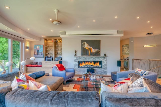 living area featuring a high end fireplace, a wall mounted AC, and recessed lighting