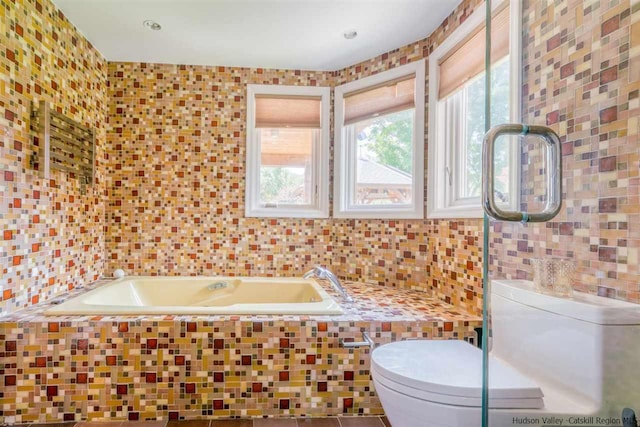 bathroom with toilet, tile walls, and a bath