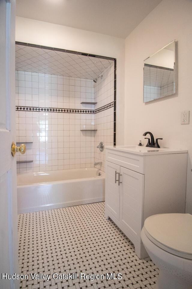 full bathroom featuring tile patterned floors, vanity, toilet, and tiled shower / bath