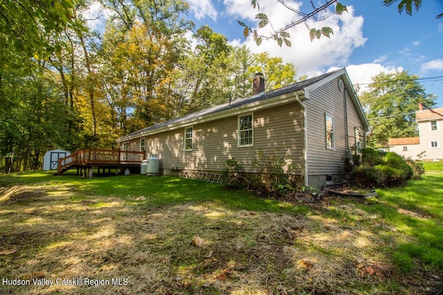 view of home's exterior featuring a deck, a storage shed, and a lawn