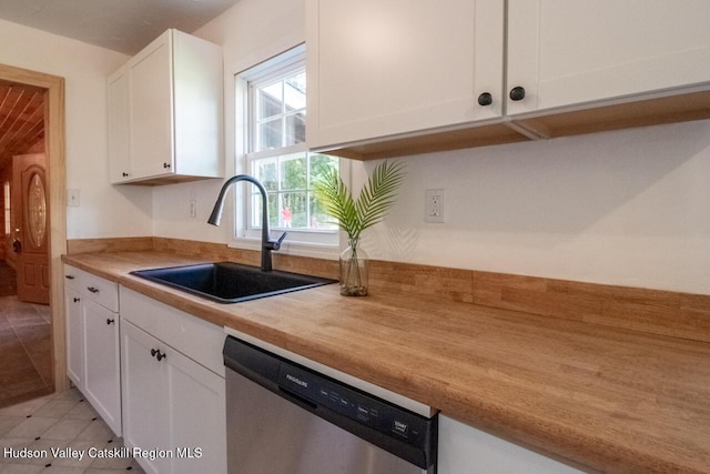 kitchen with dishwasher, light tile patterned flooring, white cabinetry, and sink