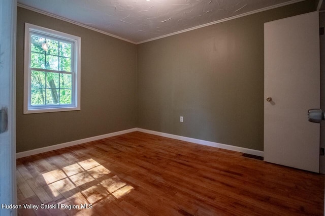 empty room featuring crown molding and hardwood / wood-style flooring