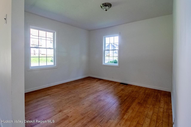 spare room featuring hardwood / wood-style floors and a healthy amount of sunlight