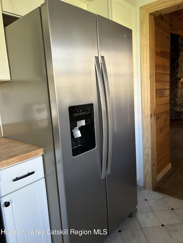 kitchen featuring white cabinets, stainless steel fridge with ice dispenser, wooden counters, and light tile patterned floors