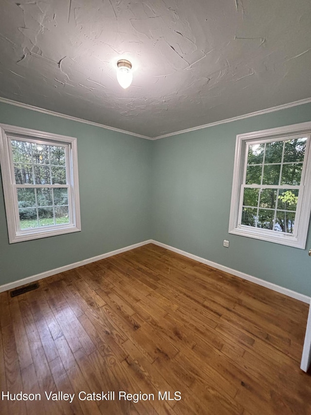 unfurnished room featuring ornamental molding and hardwood / wood-style flooring