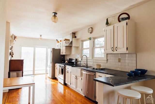 422 County Route 9, Ghent, NY 12075 - kitchen with stainless steel appliances, dark countertops, a kitchen breakfast bar, tasteful backsplash, and light wood finished floors
