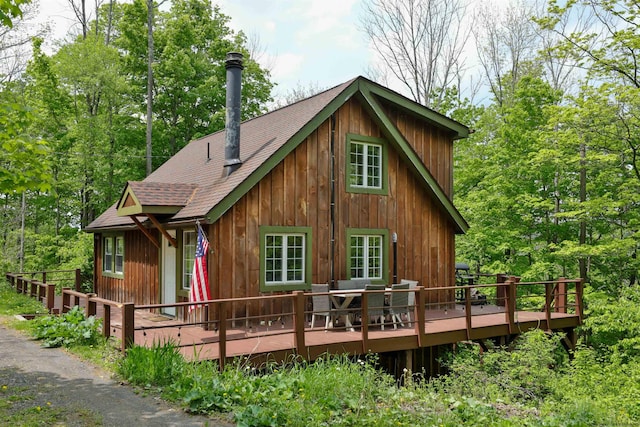 rear view of property with a deck and roof with shingles