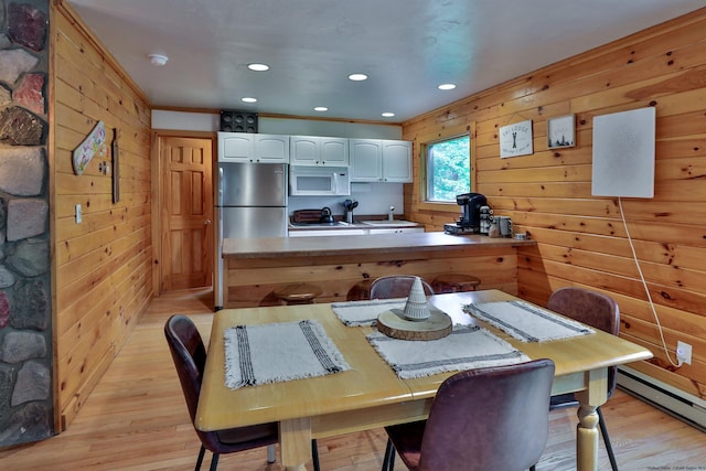 dining area featuring light wood-type flooring, wooden walls, a baseboard radiator, and recessed lighting