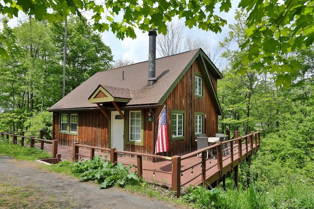 view of front facade with roof with shingles and a wooden deck