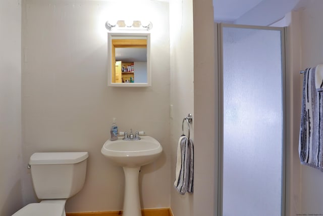 bathroom featuring a shower stall, toilet, and a sink
