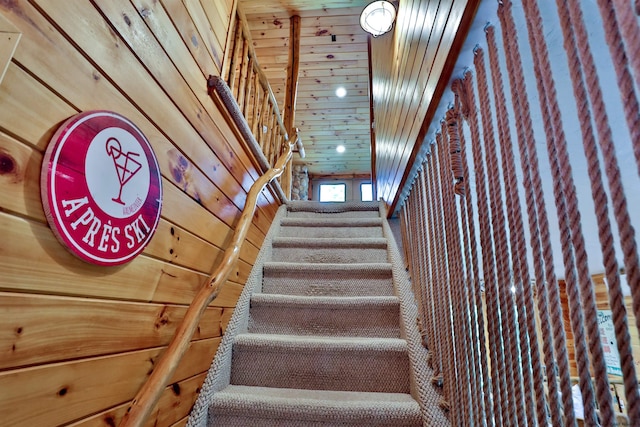 stairway featuring wood walls and wooden ceiling