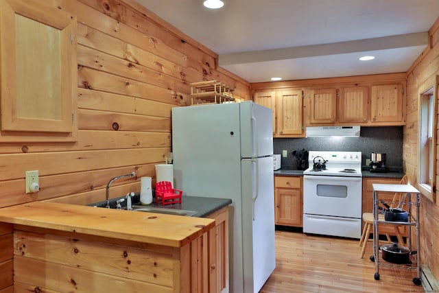 kitchen with white appliances, under cabinet range hood, a sink, light wood finished floors, and decorative backsplash