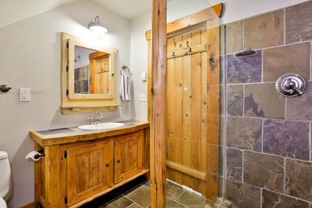 full bathroom with a tile shower, toilet, and vanity