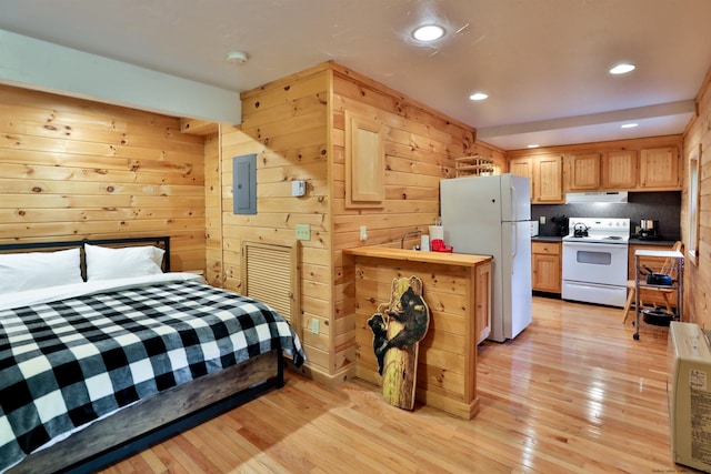 bedroom featuring freestanding refrigerator, light wood finished floors, recessed lighting, and wooden walls