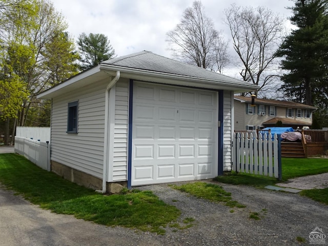 detached garage featuring fence and driveway
