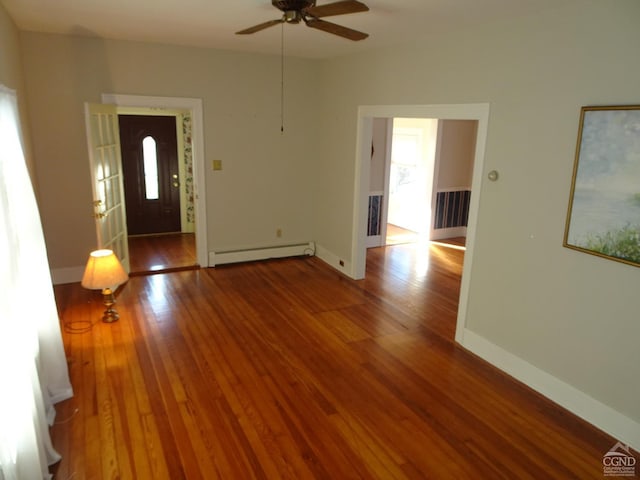 unfurnished living room featuring a baseboard heating unit, wood finished floors, a ceiling fan, and baseboards