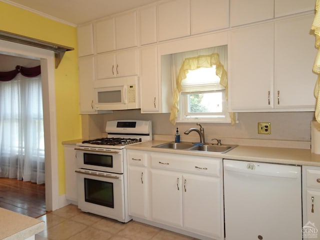 kitchen with white appliances, a sink, light countertops, white cabinetry, and crown molding