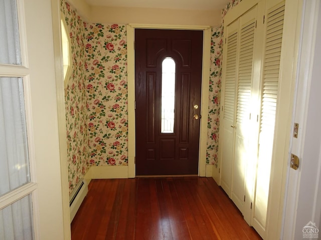 foyer entrance featuring baseboard heating, wallpapered walls, and wood-type flooring