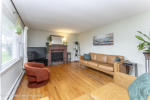 121 Rayna St, Hurley, NY 12443 - living room with baseboard heating, wood finished floors, a brick fireplace, and baseboards