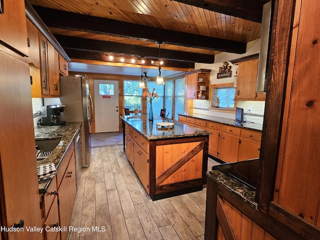 kitchen featuring plenty of natural light, a center island, beam ceiling, and light wood-style floors