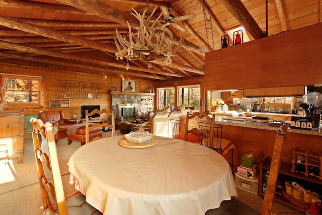 dining room featuring ceiling fan, beam ceiling, wood ceiling, and wooden walls