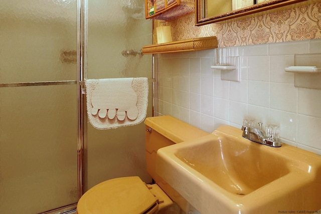 bathroom featuring decorative backsplash, toilet, a shower with shower door, and sink