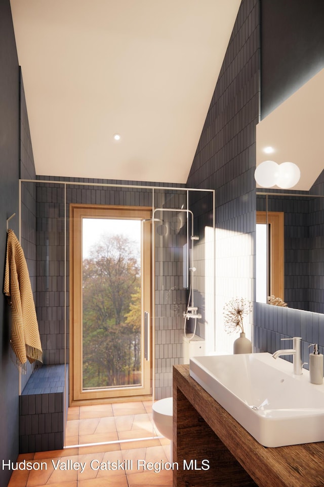 bathroom featuring a tile shower, sink, tile patterned flooring, toilet, and tile walls