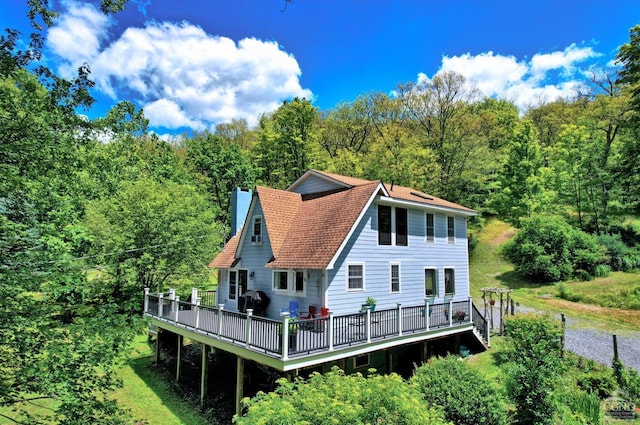 630 County Route 11, Ancram, NY 12502 - back of property with a wooden deck, a view of trees, a chimney, and a shingled roof